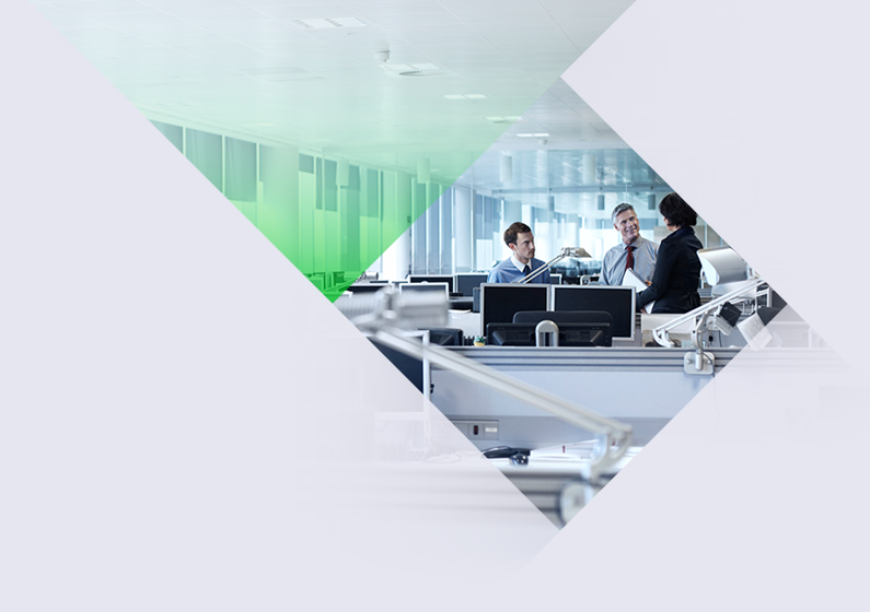 Three people in an office surrounded by computers talking.